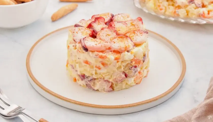 Deliciosa ensaladilla de pulpo, con patatas, zanahoria y huevo, coronada con trozos de pulpo y pimentón.