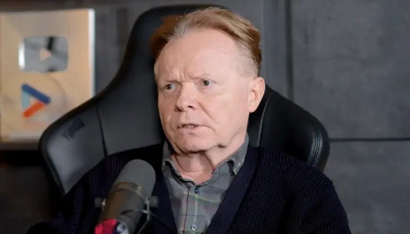Michał Bajor siedzi w fotelu, przed mikrofonem, z nagrodą YouTube w tle.