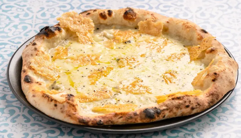 Eine köstliche Pizza Formaggi mit geschmolzenem Käse und knusprigem Rand, serviert auf einem Teller mit blau-weißem Muster.