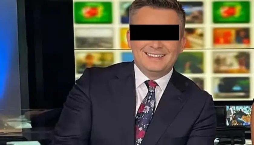 Uśmiechnięty mężczyzna w garniturze, z zasłoniętymi oczami, siedzi przed ekranami w studiu TVN. To Mateusz Walczak.