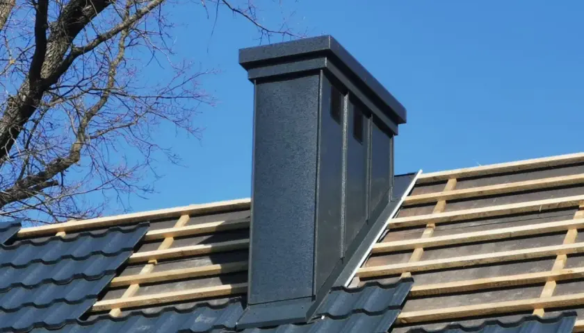 Nowy komin na dachu, widoczne łaty i kontrłaty pod dachówką.