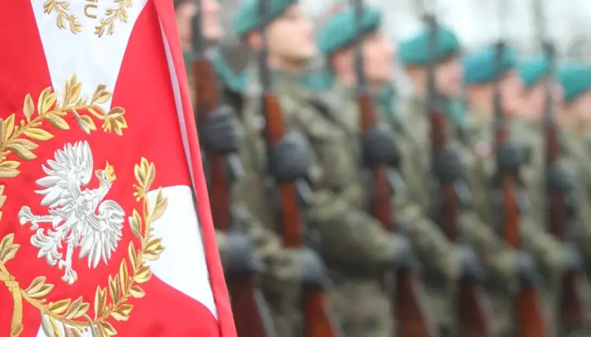 Orzeł biały na polskiej fladze i żołnierze w mundurach. Chcesz wiedzieć, jak dostać się do wojska?