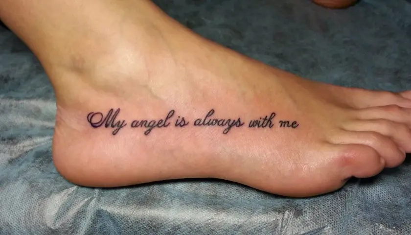 Najciekawsze tatuaż na stopie: napis "My angel is always with me" w eleganckiej czcionce.