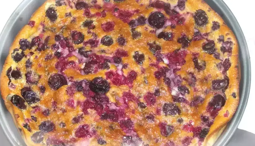 Un délicieux clafouti aux fruits rouges, tout juste sorti du four, avec ses myrtilles et framboises fondantes.