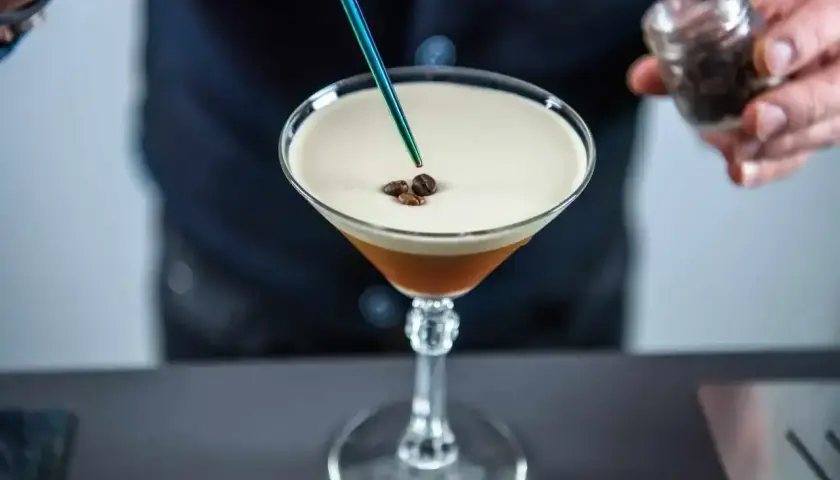 Barman dodaje ziarna kawy do drinka z pianką, przypominającego Espresso Martini. To właśnie kahlua co to za likier?