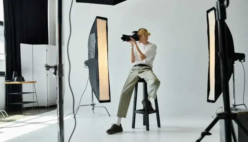 Młody fotograf w studio, z aparatem w ręku, zastanawia się, ile zarabia fotograf.