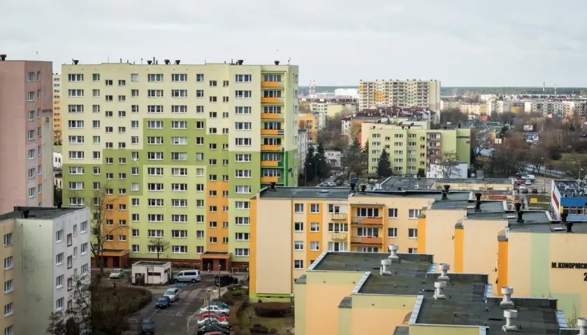 Widok na osiedle wielopiętrowych bloków mieszkalnych w pastelowych kolorach.