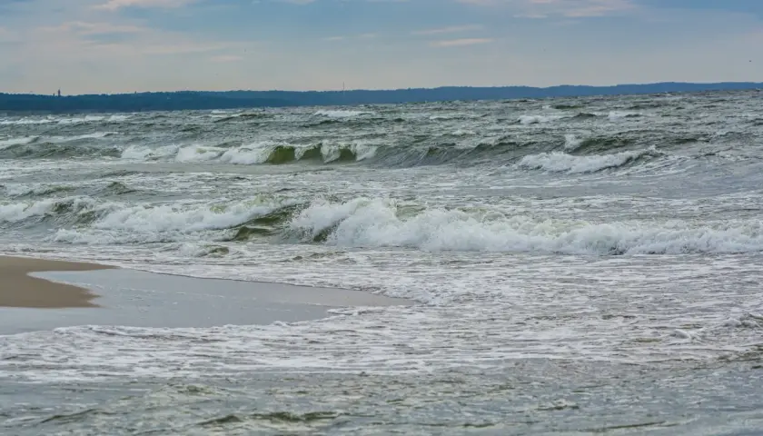Fale rozbijają się o brzeg. Zastanawiasz się, co robić zimą nad morzem? Spacer po plaży i podziwianie żywiołu to świetny pomysł.