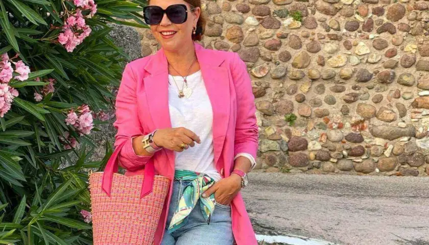 Kobieta w różowej marynarce i jeansach, z torebką i apaszką, tworzy idealny outfit na randkę.