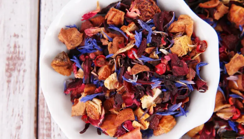 Mieszanka suszone owoce do herbaty: kawałki jabłek, hibiskus, płatki róży i chabru tworzą barwny bukiet.
