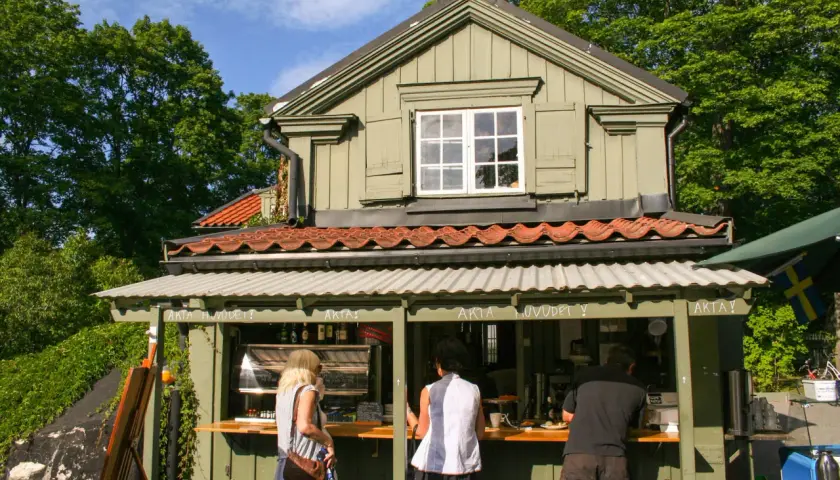 Vid Waldemarsudde café beställer folk fika i solen.
