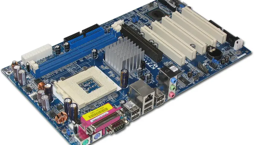 Carte mère d'ordinateur bleue avec dissipateur thermique, connecteurs RAM, PCI et ports d'entrée/sortie.