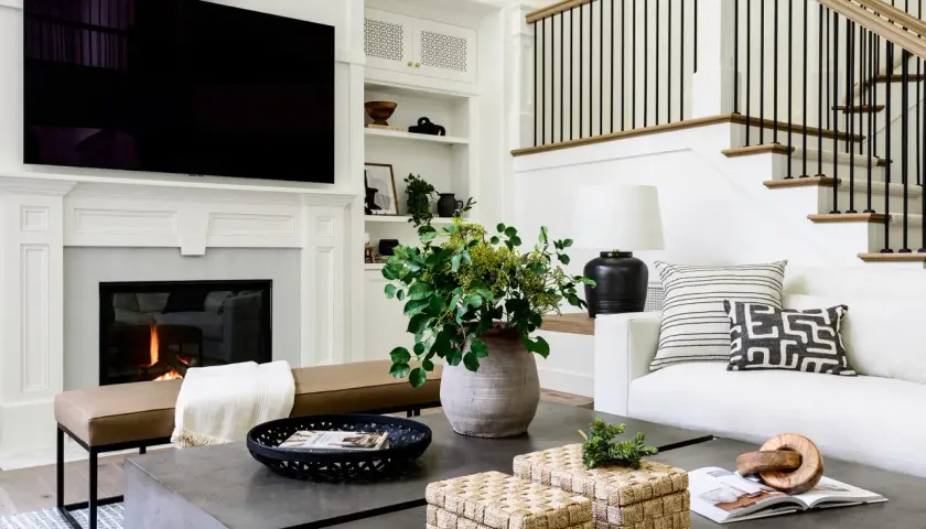 Stylish coffee table decor ideas: woven boxes, a black tray with a magazine, and a large vase with greenery.