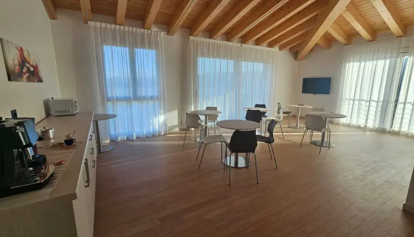 Pavimento per mansarda in legno chiaro, con travi a vista e arredi moderni.
