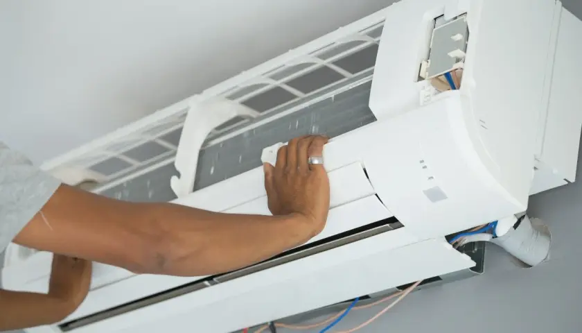 Mano ajustando el cepillo para limpiar la turbina del aire acondicionado.