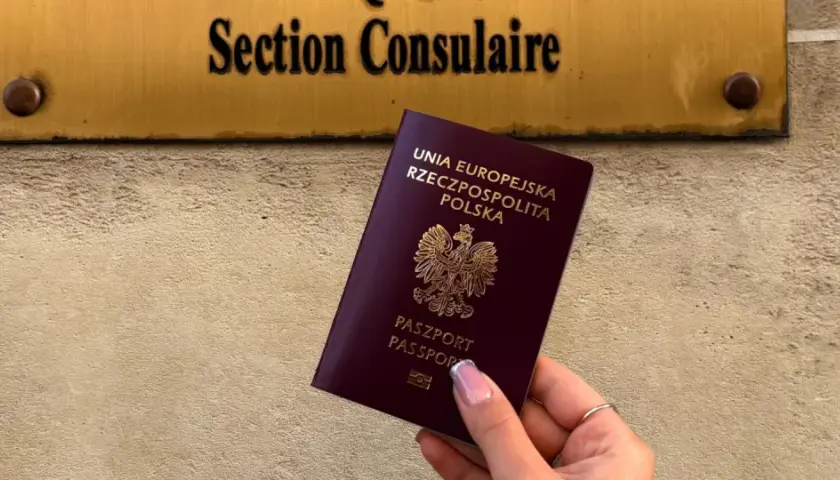 Polski paszport w dłoni przed tabliczką "Section Consulaire". Czy do Francji trzeba paszport? Tak, jeśli nie jesteś obywatelem UE.