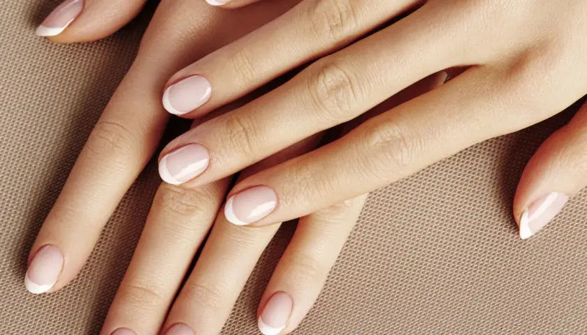 Dłonie z perfekcyjnym manicurem w stylu kok francuski. Delikatny róż i białe końcówki paznokci.