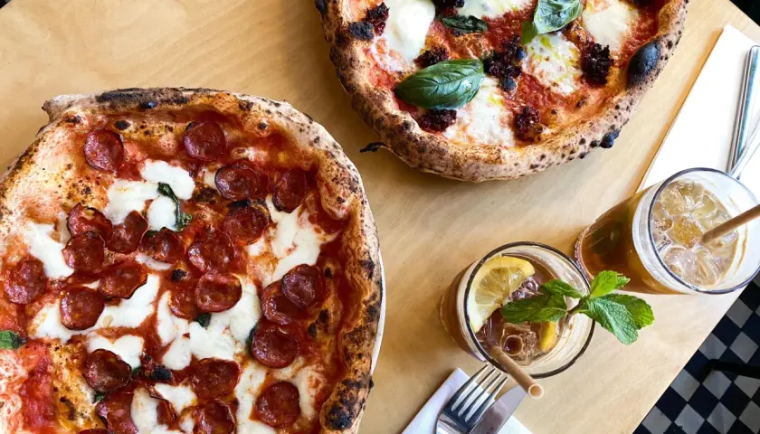Dwie pyszne pizze, jedna z salami, druga z pomidorami i mozzarellą, idealne na najlepszą pizzę Warszawa. Do tego orzeźwiające napoje.