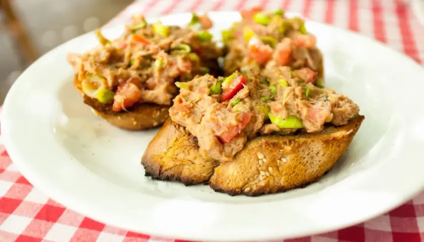 Trzy chrupiące kromki chleba z pastą z tuńczyka, pomidorów i zielonej cebulki. Idealna bruschetta z tuńczykiem na letni obiad.