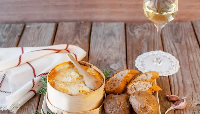 Un Mont d'Or au four, pommes de terre, pain et vin blanc. Quel vin avec Mont d'Or au four ? Un accord parfait pour un repas convivial.