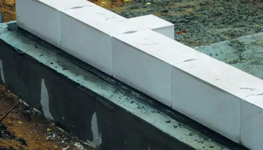 Białe pustaki betonowe układane na fundamencie. Kluczowe są właściwe zaprawa murarska proporcje, by konstrukcja była trwała.