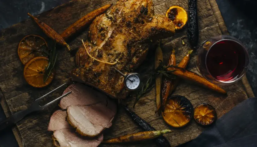 Un rôti de porc savoureux, accompagné de carottes rôties, d'oranges caramélisées et d'un verre de vin rouge. Parfait pour un repas d'automne.
