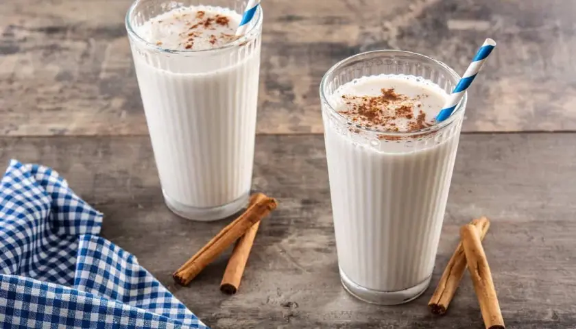 Dos vasos de horchata, bebida refrescante de chufa con canela, sobre mesa de madera.