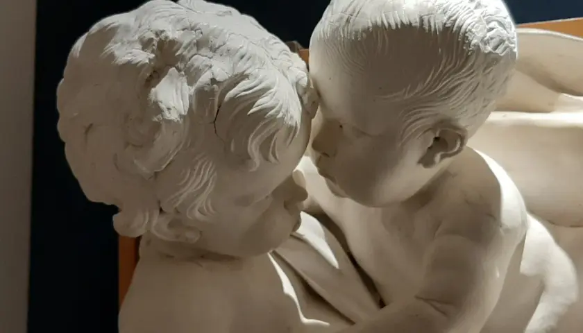 Due putti in stucco, un'opera di Giacomo Serpotta, si abbracciano teneramente.