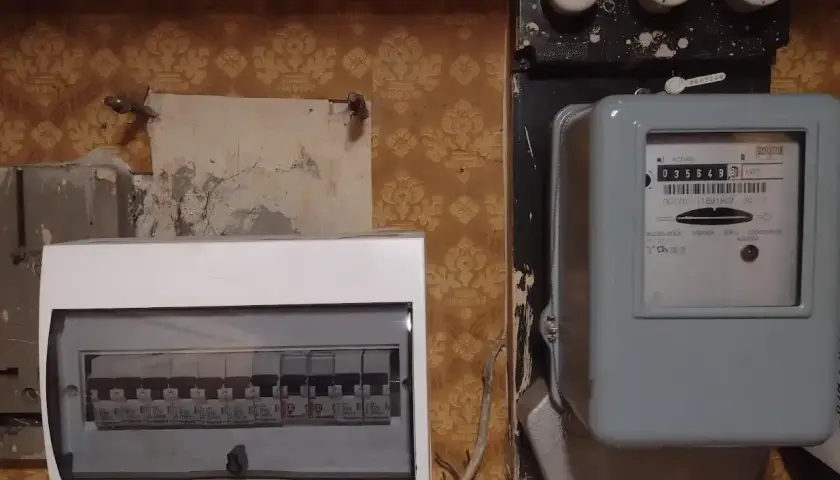 Zabezpieczenie przedlicznikowe obok licznika energii elektrycznej i białej skrzynki z bezpiecznikami.