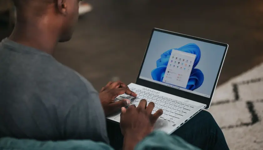 Mężczyzna na laptopie z systemem Windows 11, szukający informacji, jak zmienić nazwę użytkownika Windows 11.