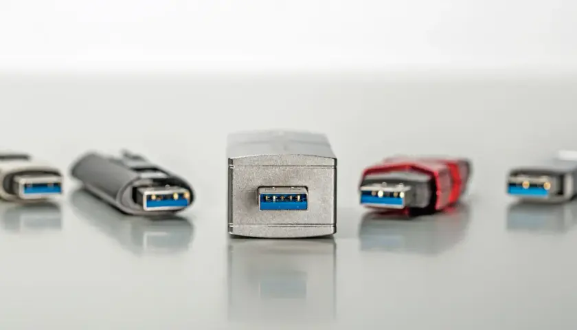 Fünf USB-Sticks in verschiedenen Designs, alle mit blauem Anschluss. Einer davon, der mittlere, wirkt besonders robust, fast wie ein Relikt aus der Zeit der USB 1.0 Geschwindigkeit.