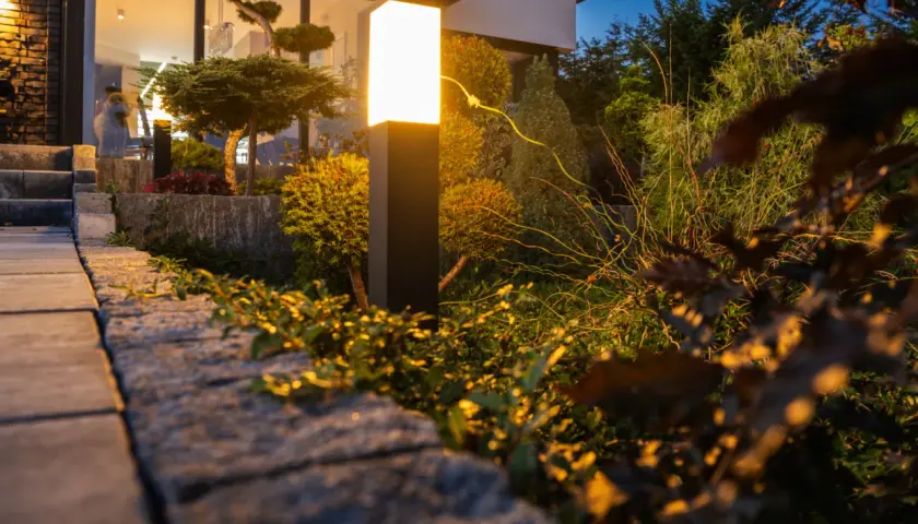 Nowoczesna lampa oświetla ogród, tworząc magiczną atmosferę. Zobacz, jak oświetlić ogród, by był piękny nocą.