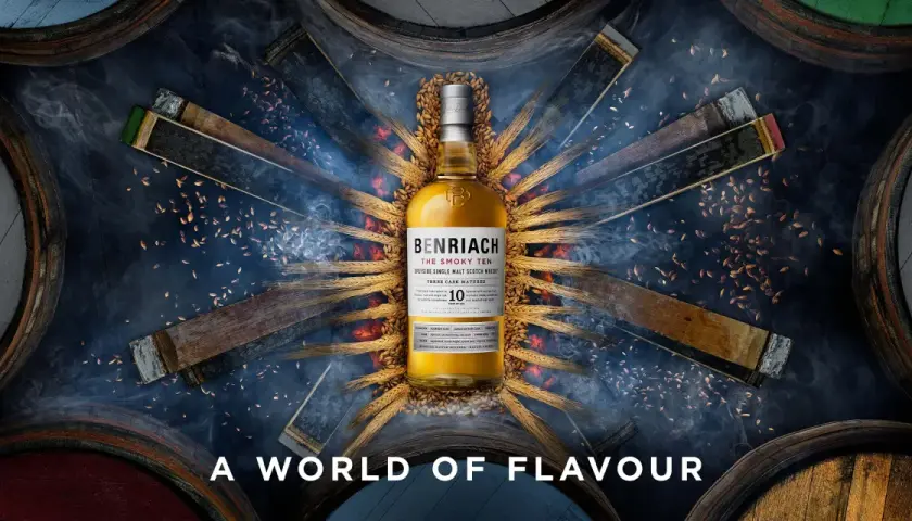 Bouteille de whisky BenRiach The Smoky Ten, entourée de fûts et d'épis de blé, évoquant le savoir-faire de la distillerie.