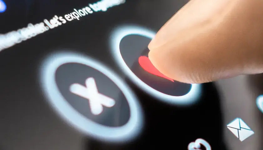 Palec dotyka serca na ekranie telefonu, wybierając potencjalną randkę. Aplikacje randkowe na telefon ułatwiają poznawanie nowych ludzi.