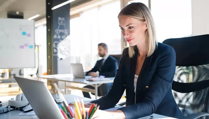 Eine Frau am Laptop, die die master digitalisierung vorantreibt. Im Hintergrund ein Kollege.
