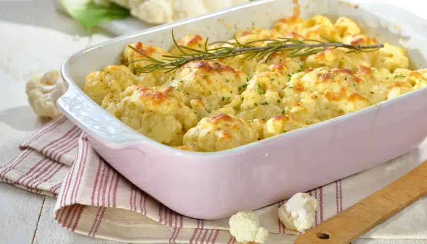 Cavolfiore al forno con pangrattato e formaggio fuso, guarnito con rosmarino fresco. Un piatto invitante e saporito.