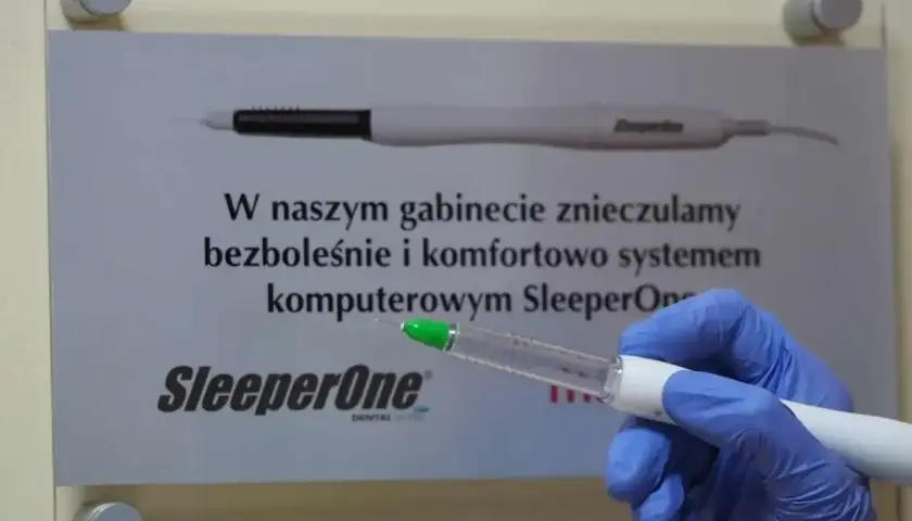 Ręka w niebieskiej rękawiczce trzyma komputerowy system znieczulający SleeperOne. Dowiedz się, ile trzyma znieczulenie u dentysty.