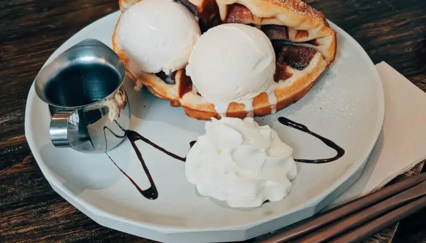 Pyszne bacio lody na ciepłym gofrze z bitą śmietaną i polewą czekoladową. Idealny deser na każdą okazję.