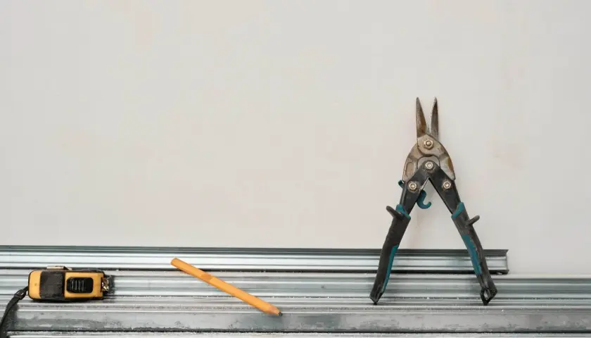 Outils pour comment couper un rail de placo : cisaille, mètre, crayon. Prêt à construire !