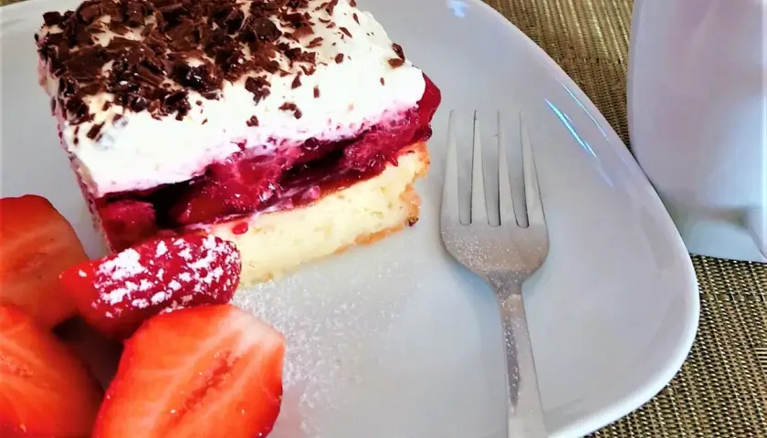 Pyszny biszkopt z galaretką i kremem mascarpone, udekorowany startą czekoladą i świeżymi truskawkami. Idealny deser.
