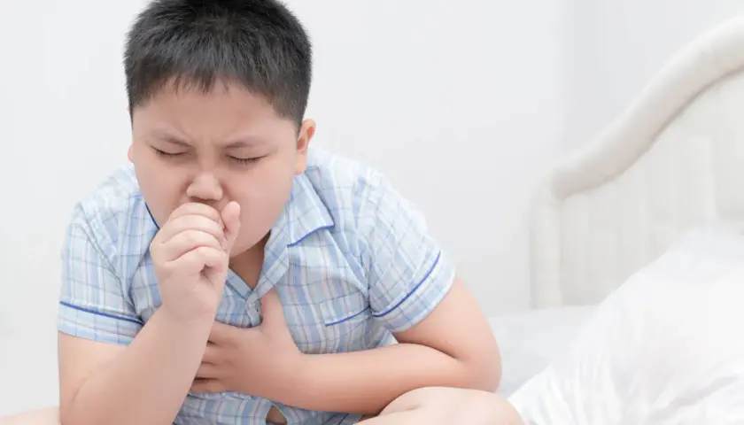 Niño con tos, con la mano en la boca y el pecho. ¿Cuándo preocuparse por tos en niños?