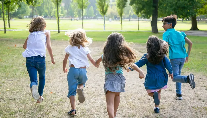 Niños corriendo en un parque, disfrutando de la **infantil primavera**.