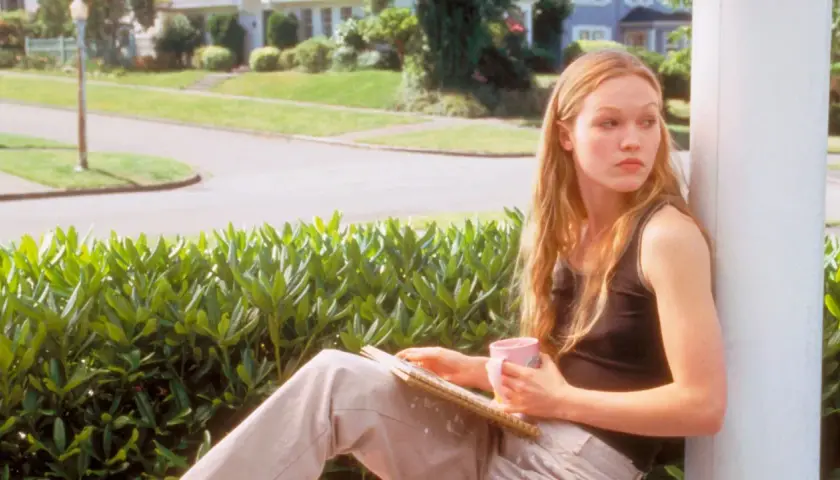 Kat Stratford, protagonista di "10 cose che odio di te trama", pensierosa con una tazza rosa e un quaderno.