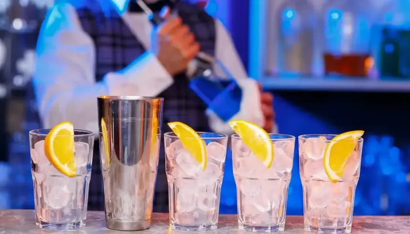 Barman przygotowuje drinki. Zastanawiasz się, ile kosztuje kurs barmanski? Zobacz, jak powstają drinki z lodem i pomarańczą.