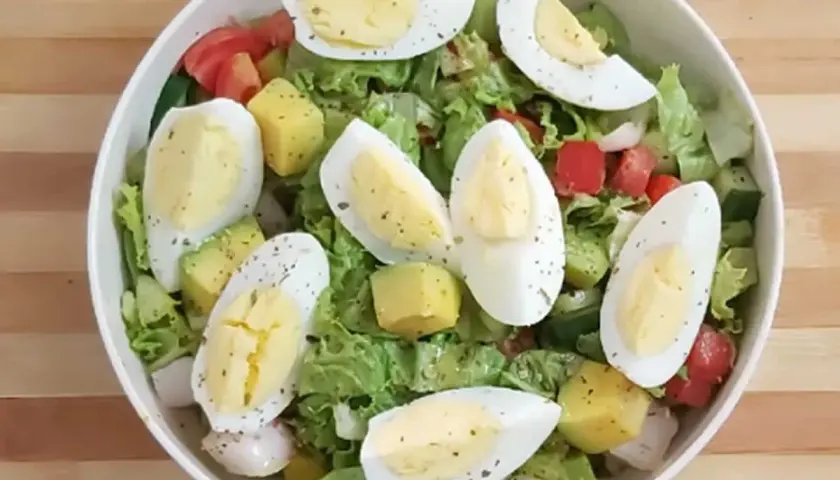 Salade colorée avec avocat, œuf dur coupé en quartiers, tomates, concombres et laitue. Un délice frais et équilibré.