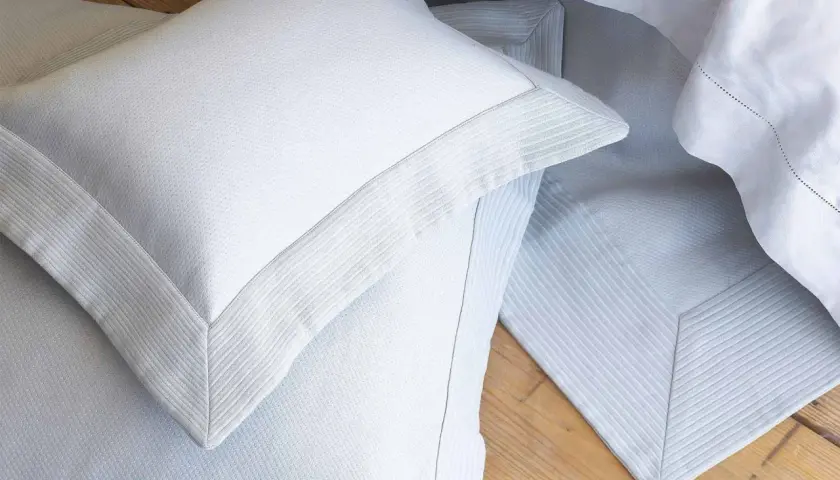 Close-up of white pillow shams with decorative borders, often used to dress up a bed and protect pillows.