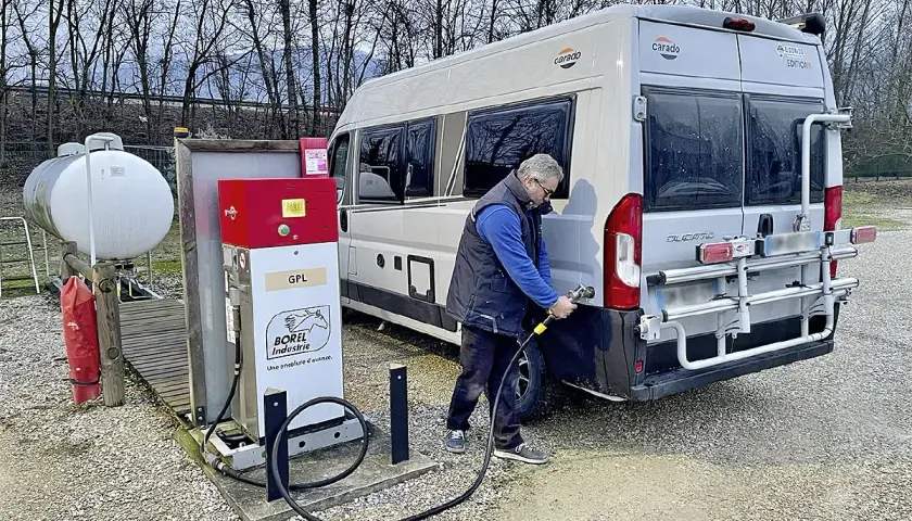Un homme fait le plein de son camping-car à une pompe GPL. Le bon gaz pour camping car est le GPL.