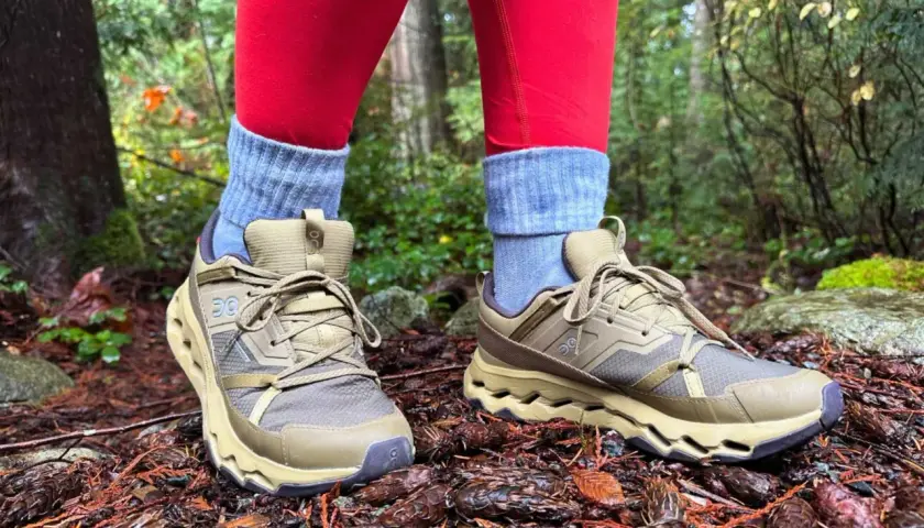 These tan hiking shoes with grey socks and red leggings are perfect for exploring a forest floor covered in pinecones.
