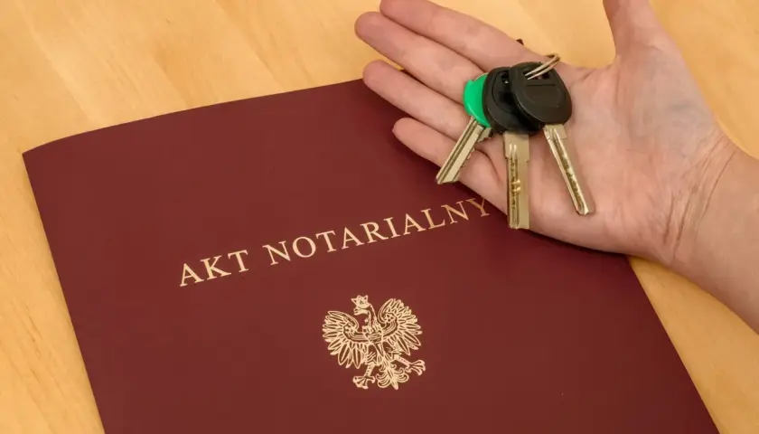 Dłoń z kluczami spoczywa na akcie notarialnym o majątku osobistym.