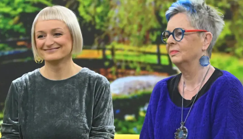 Dwie kobiety, jedna z krótkimi blond włosami, druga z siwymi z niebieskimi pasemkami, rozmawiają. Może facet 30 lat bez dziewczyny szuka rady u przyjaciółki?